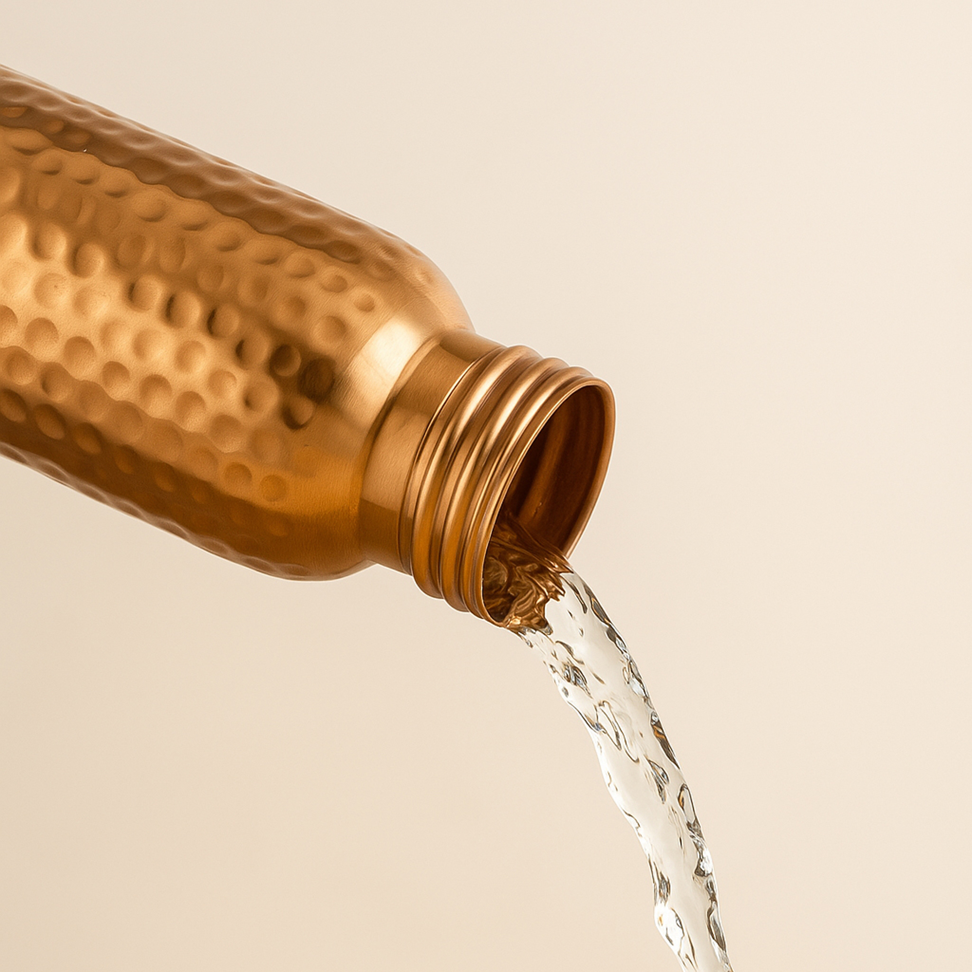 Pure water pouring from a hammered copper water bottle